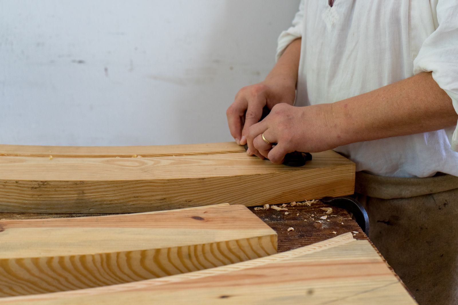 A craftsman planing a length of timber at a workbench